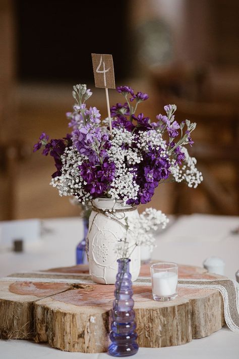 White mason jar centrepiece with purple and white flowers and a burlap table number. Lavender & Plum Wedding Ideas